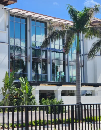 A white building with palm trees in front of it.